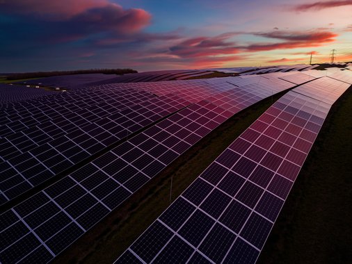 A purple sunset reflects onto a solar farm