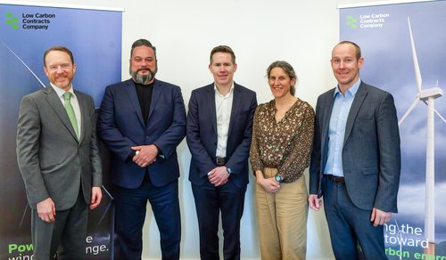 Five people, dressed in business attire, stand in front of two LCCC pull up banners.